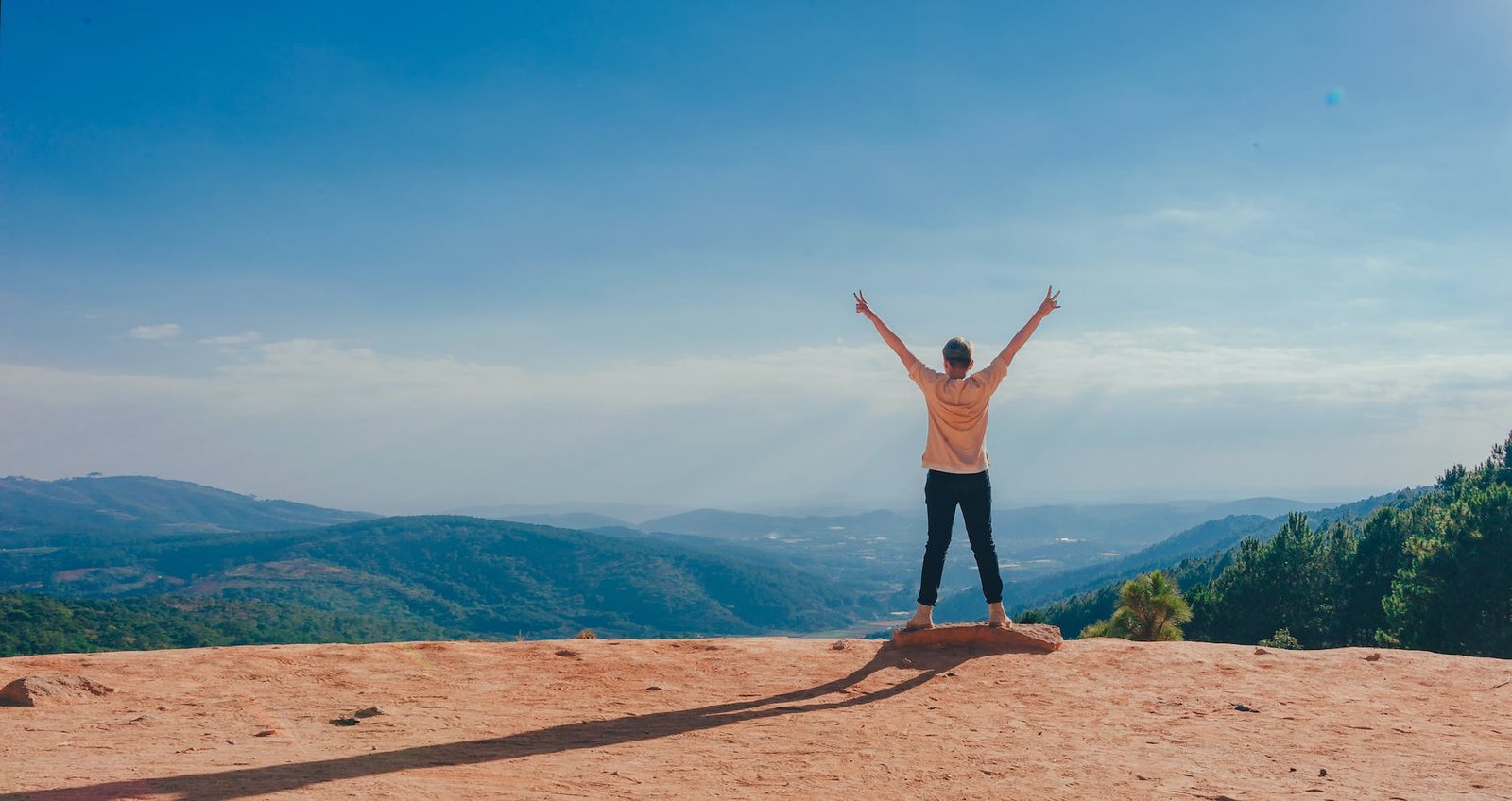 person in beige top on mountain cliff