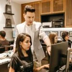 man teaching woman in front of monitor